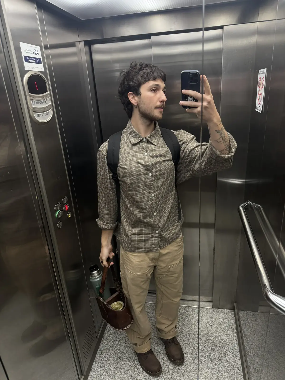 Foto de ejemplo de un outfit con camisa a cuadros verde oliva, pantalón beige, botas marrones y un bolso marrón